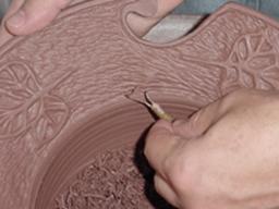Mike Ware decorates his work by incising and carving the clay surface.